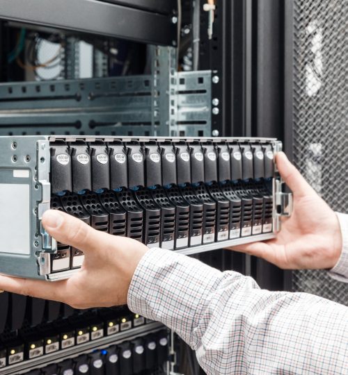 IT Engineer installs enclosure with hard disk drive in the storage system in the rack in datacenter